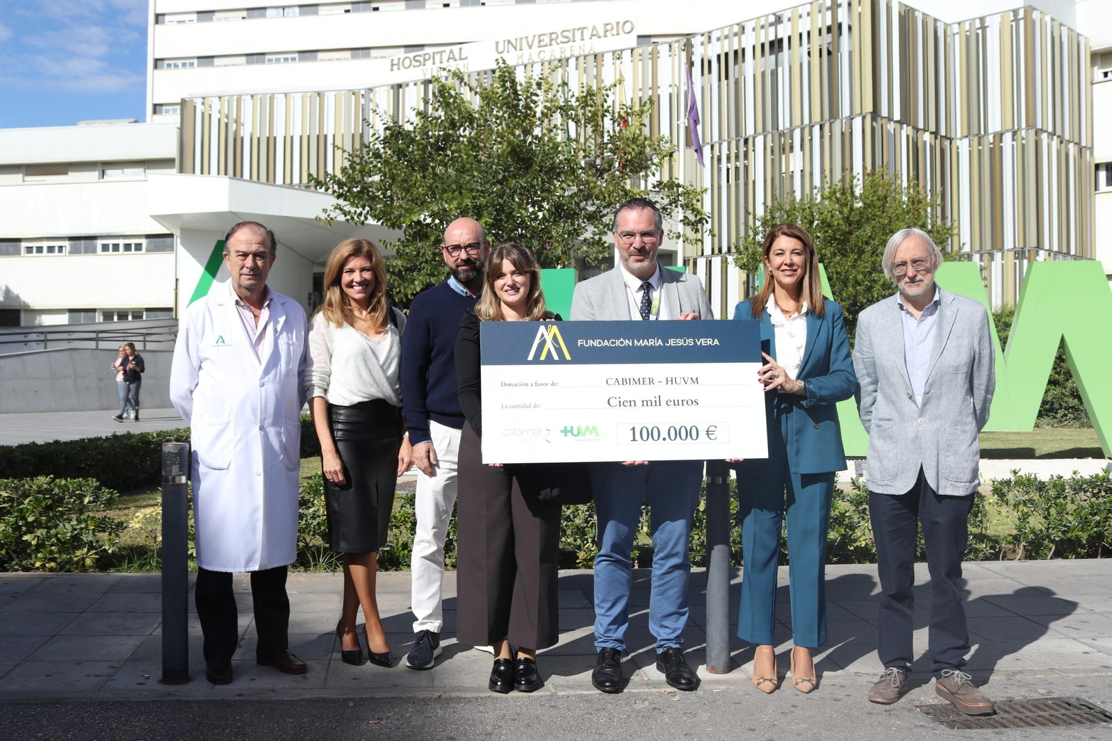 El doctor Luis de la Cruz y la investigadora Patricia Altea, junto a las autoridades, sostienen el cheque.