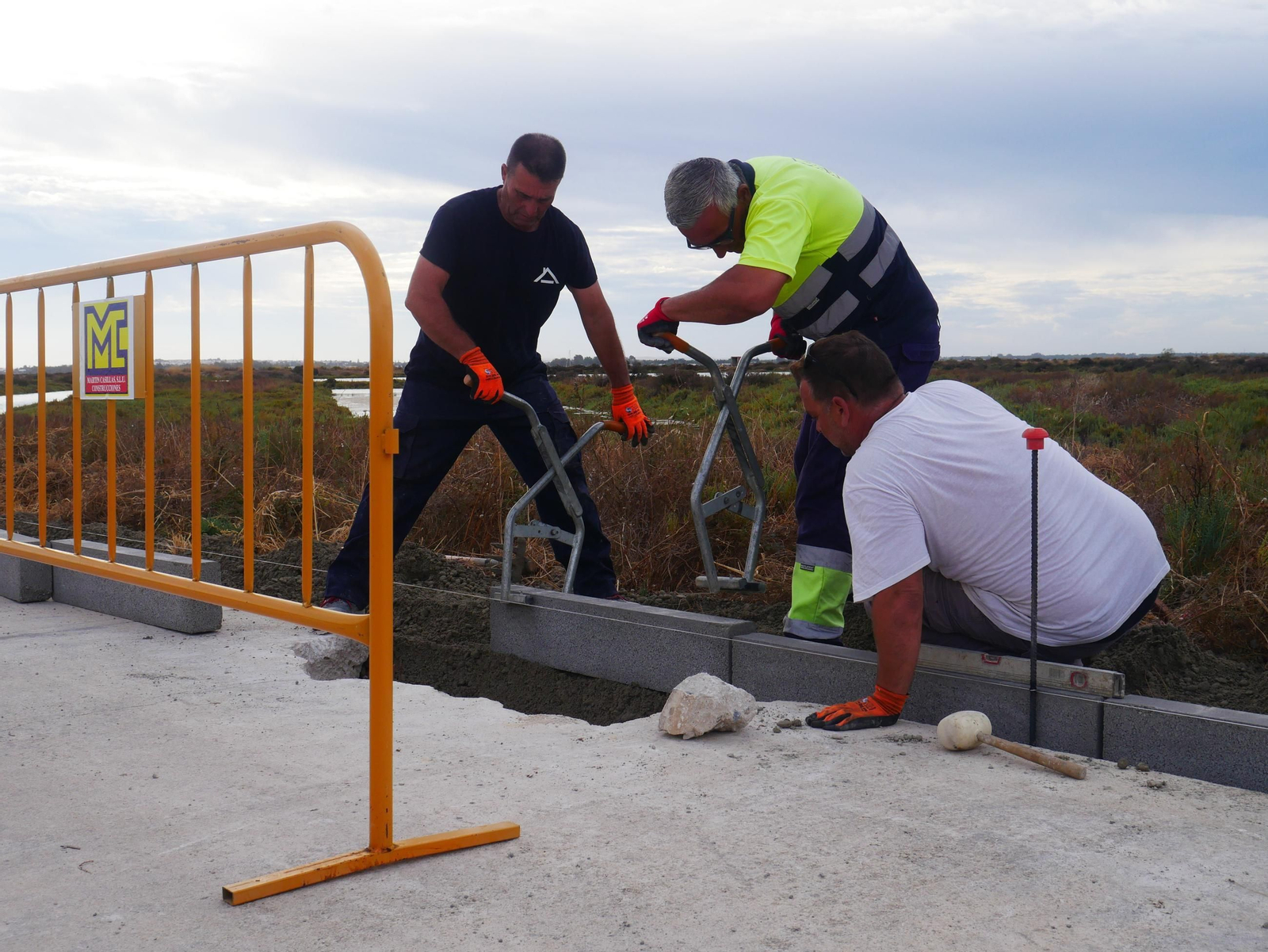Operarios, colocando los bordillos que delimitarán el paseo marítimo.