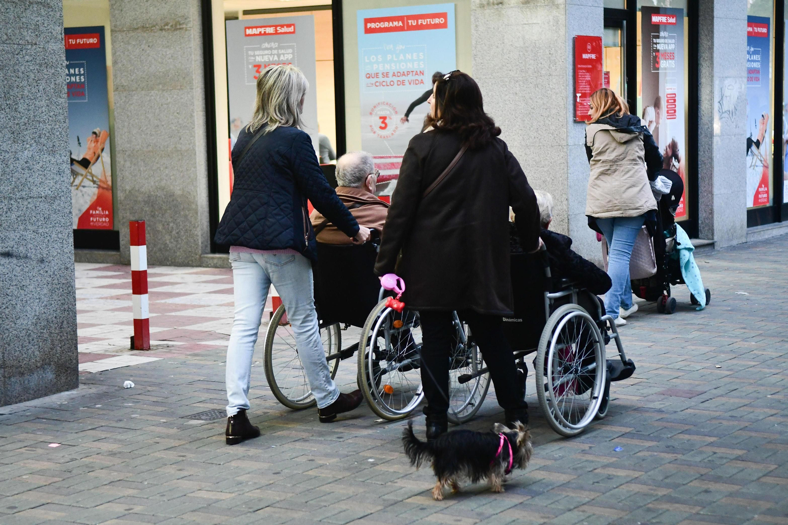 Dos mujeres ayudan a otras dos personas en sillas de ruedas.
