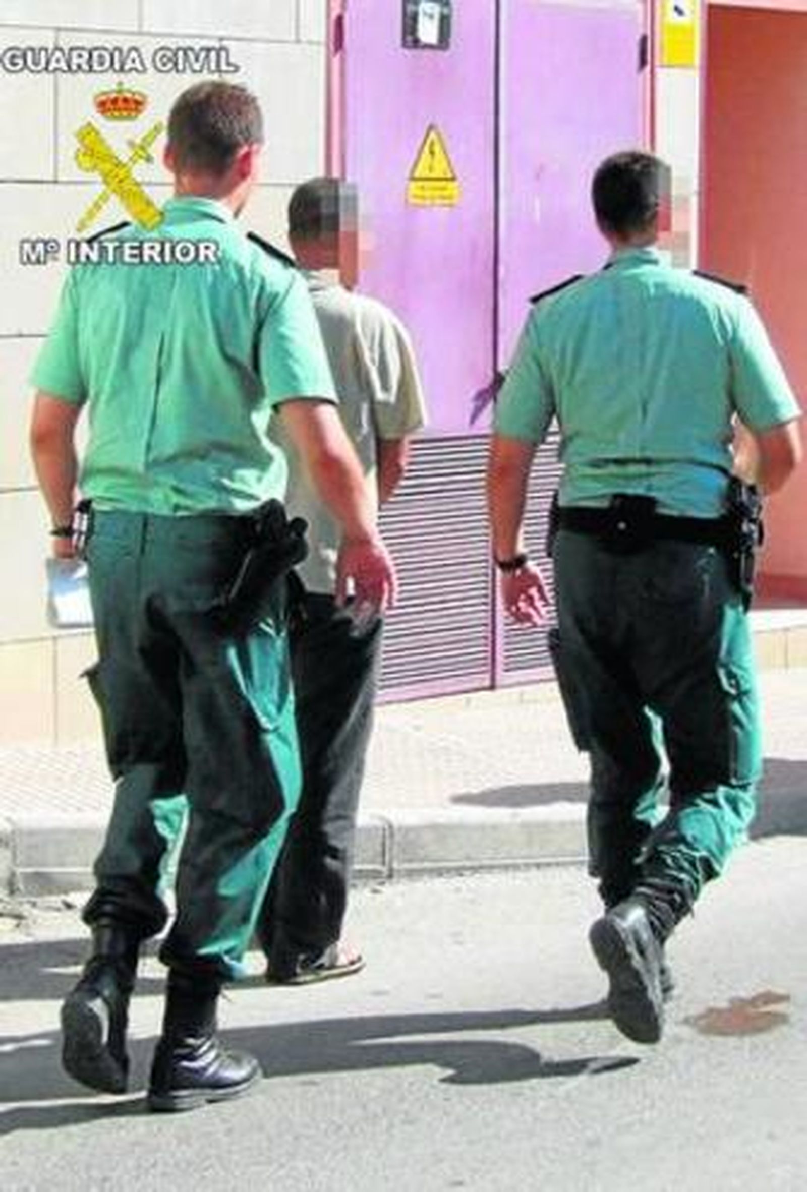 Agentes de la Guardia Civil custodian a uno de los detenidos.