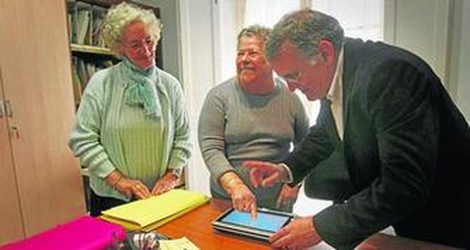 Dos de las voluntarias de la Matías Calvo aprenden a usar la pantalla táctil gracias a un prototipo que les muestra el coordinador del proyecto.