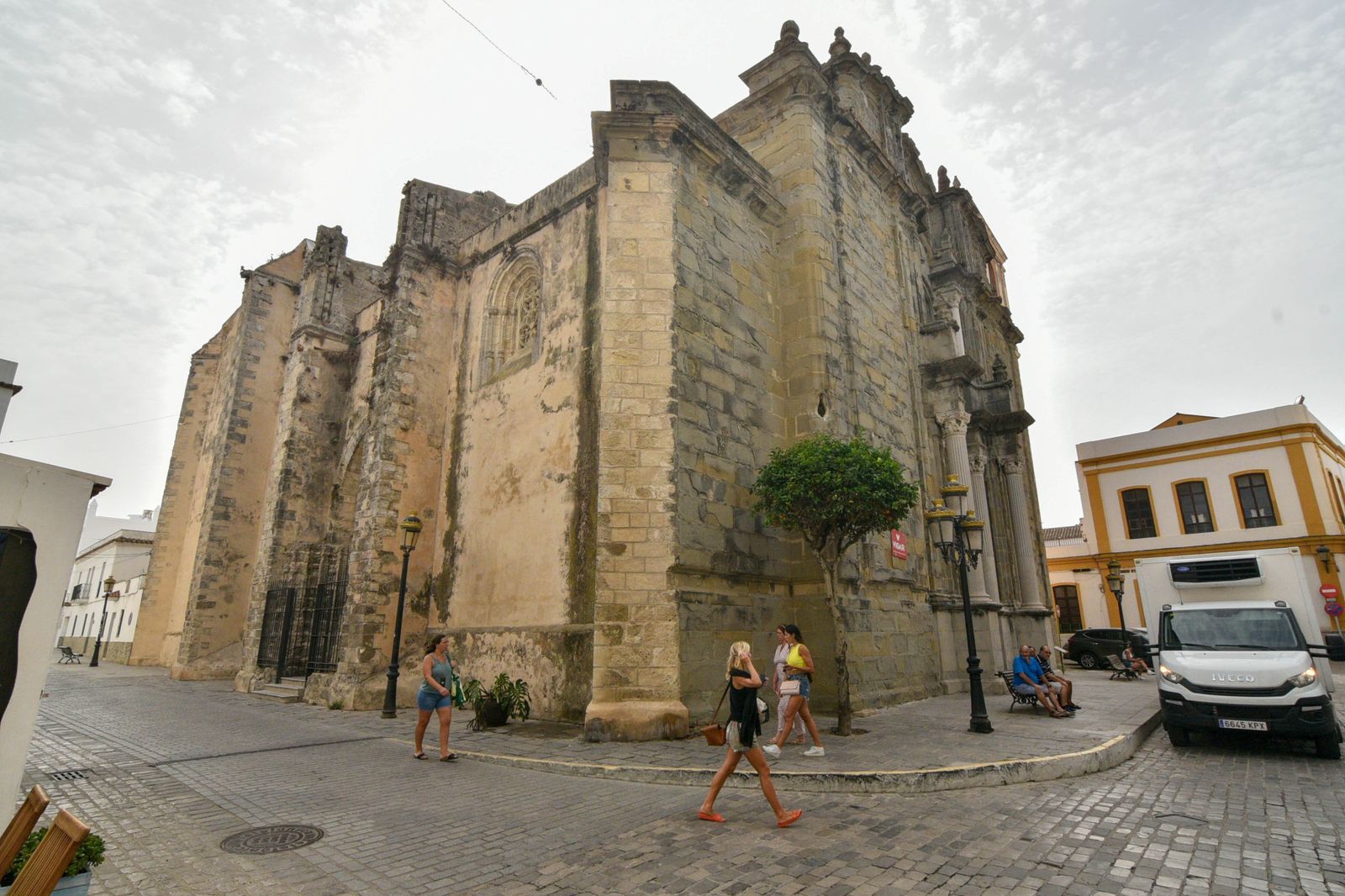 Varias personas caminan junto a la parroquia de San Mateo, en el casco histórico de Tarifa.