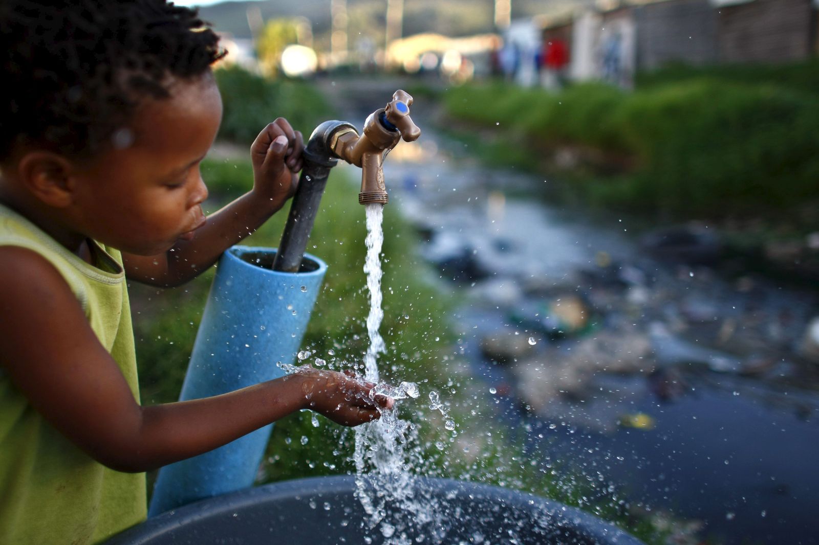Un niño saca agua de un grifo.