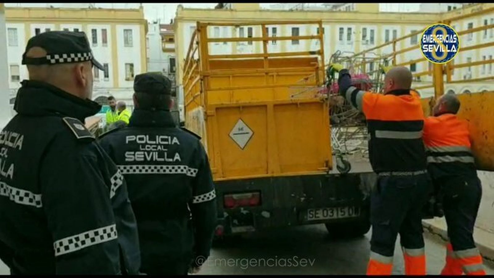 Operarios de Lipasam cargan los residuos retirados ante la mirada de dos policías locales.