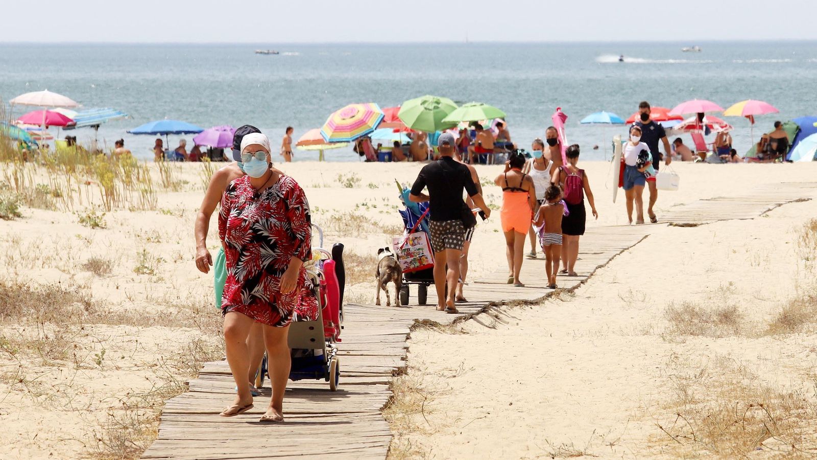 Onubenses y turistas acceden a la costa por la pasarela de madera.