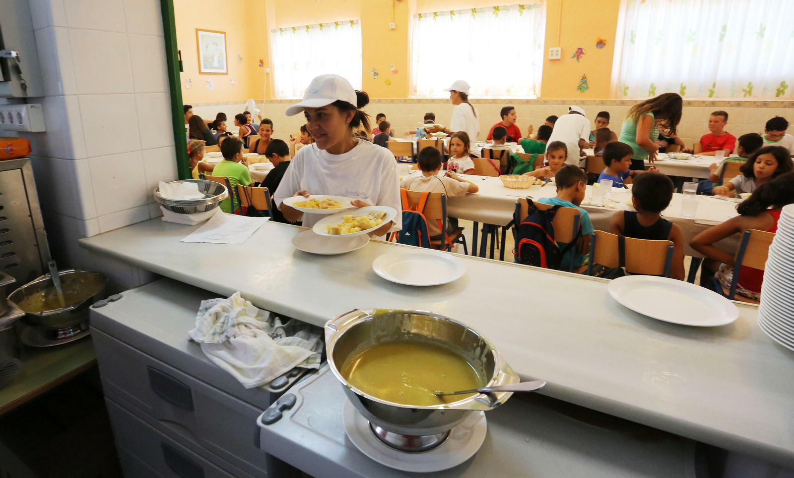 Una trabajadora recoge unos platos en un servicio de comedor escolar.