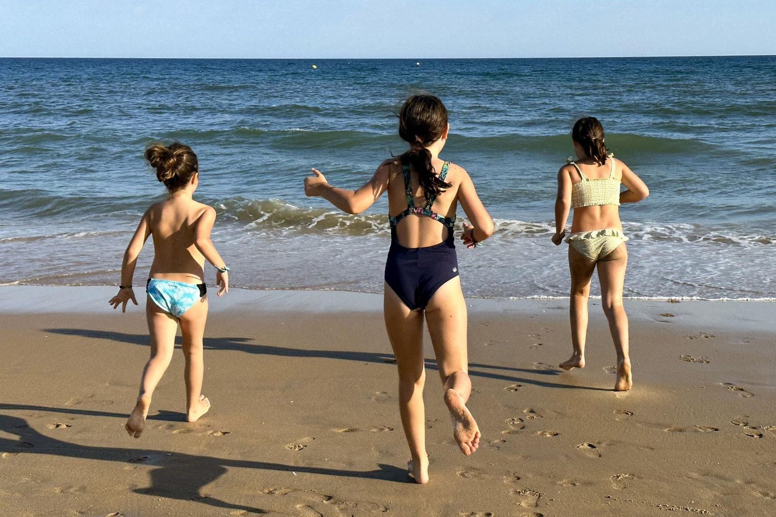 Tres niñas juegan en una playa.