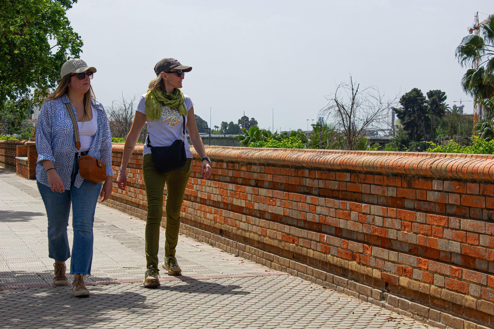 Dos personas pasean ante el muro del Paseo de las Delicias.