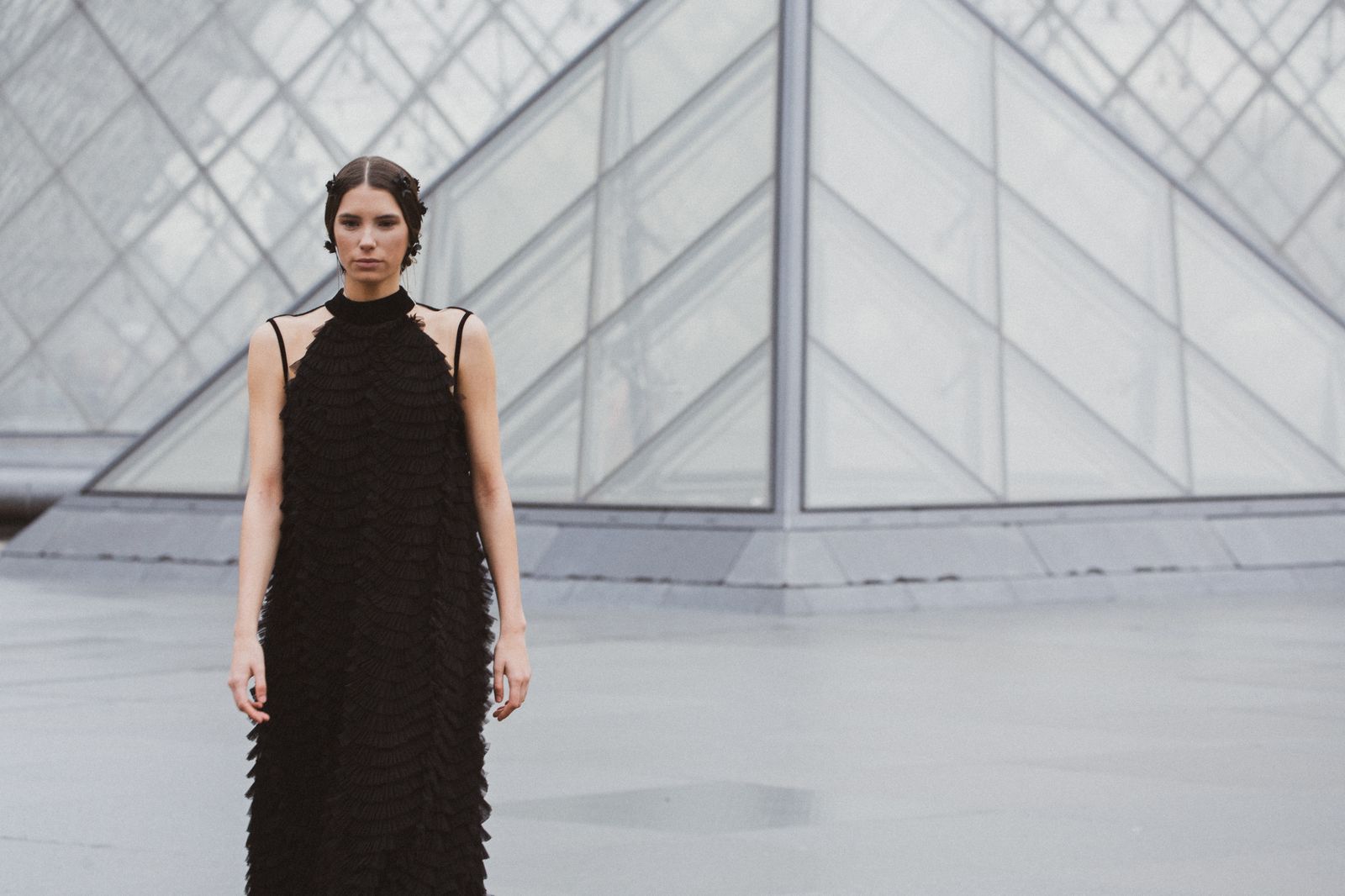 Una modelo posa con un diseño de Pilar Dalbat frente a la icónica pirámide de cristal del Museo del Louvre