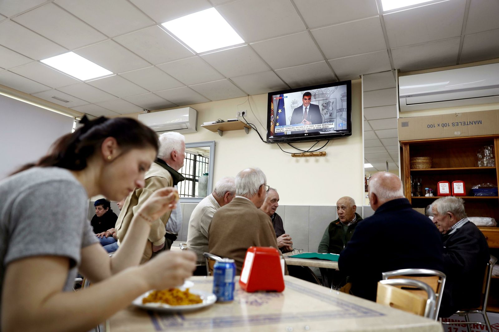 Un grupo de ancianos, al fondo, juega a las cartas en un bar de Madrid.