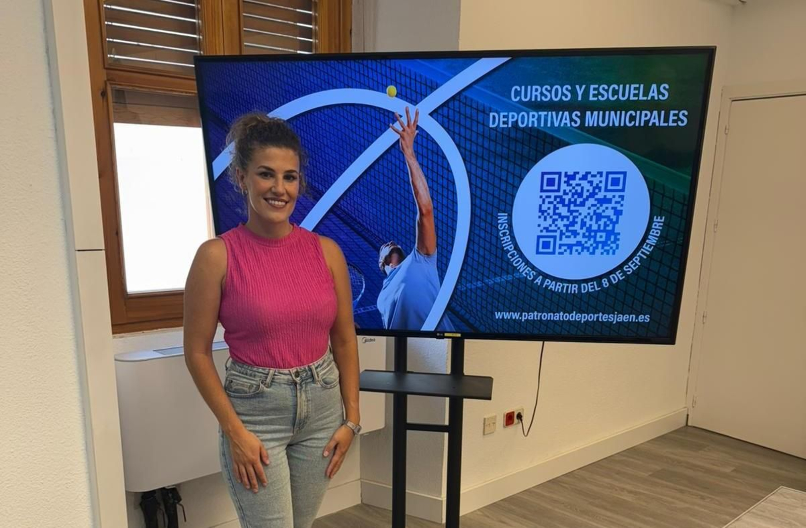 Beatriz López posa junto al cartel informativo de los cursos y escuelas deportivas municipales.