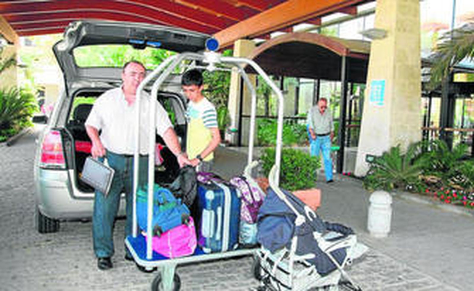 Unos turistas decargan las maletas a las puertas de un hotel de Huelva.