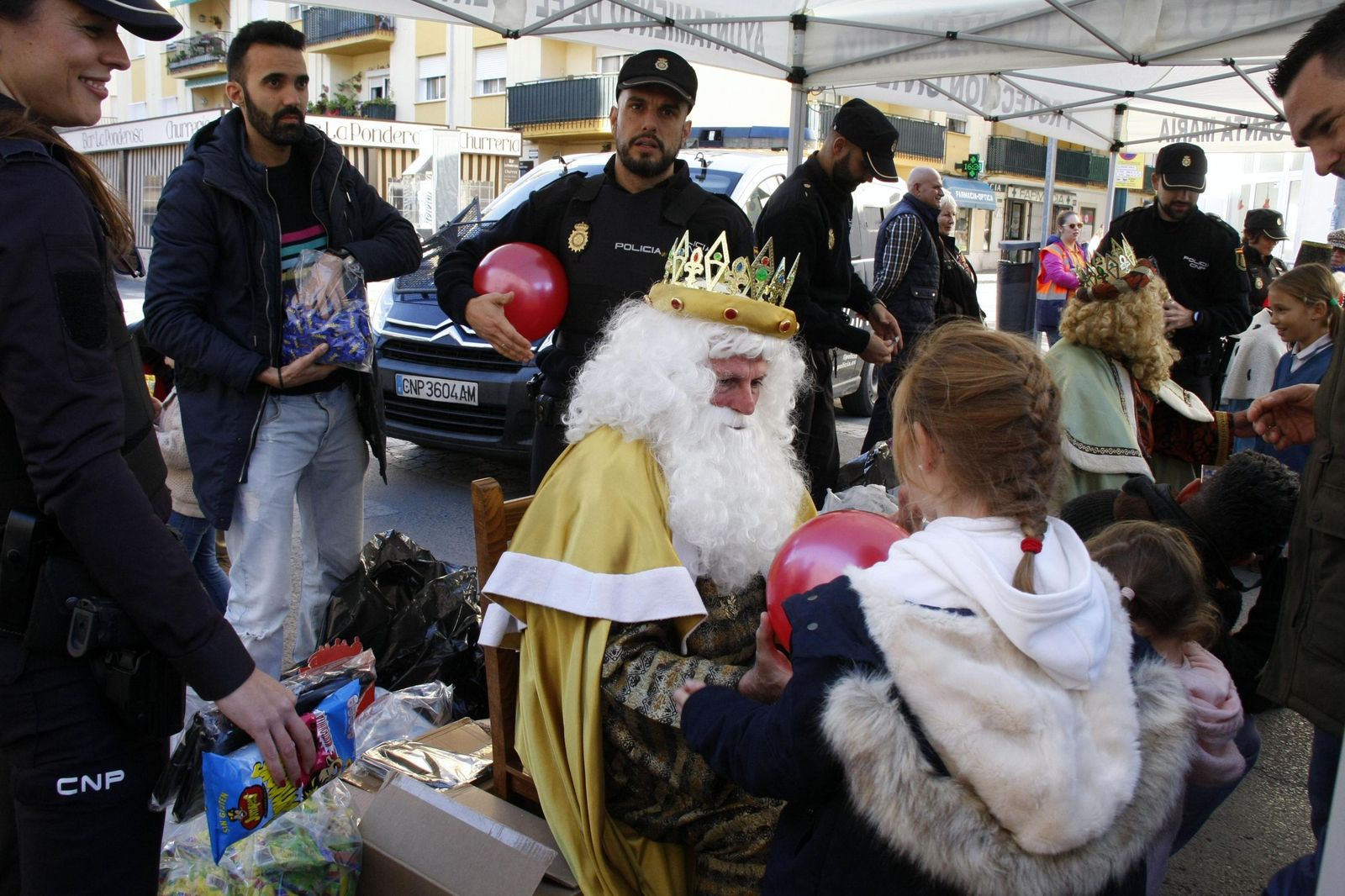 Uno de los Reyes Magos, entregando una pelota a una niña.