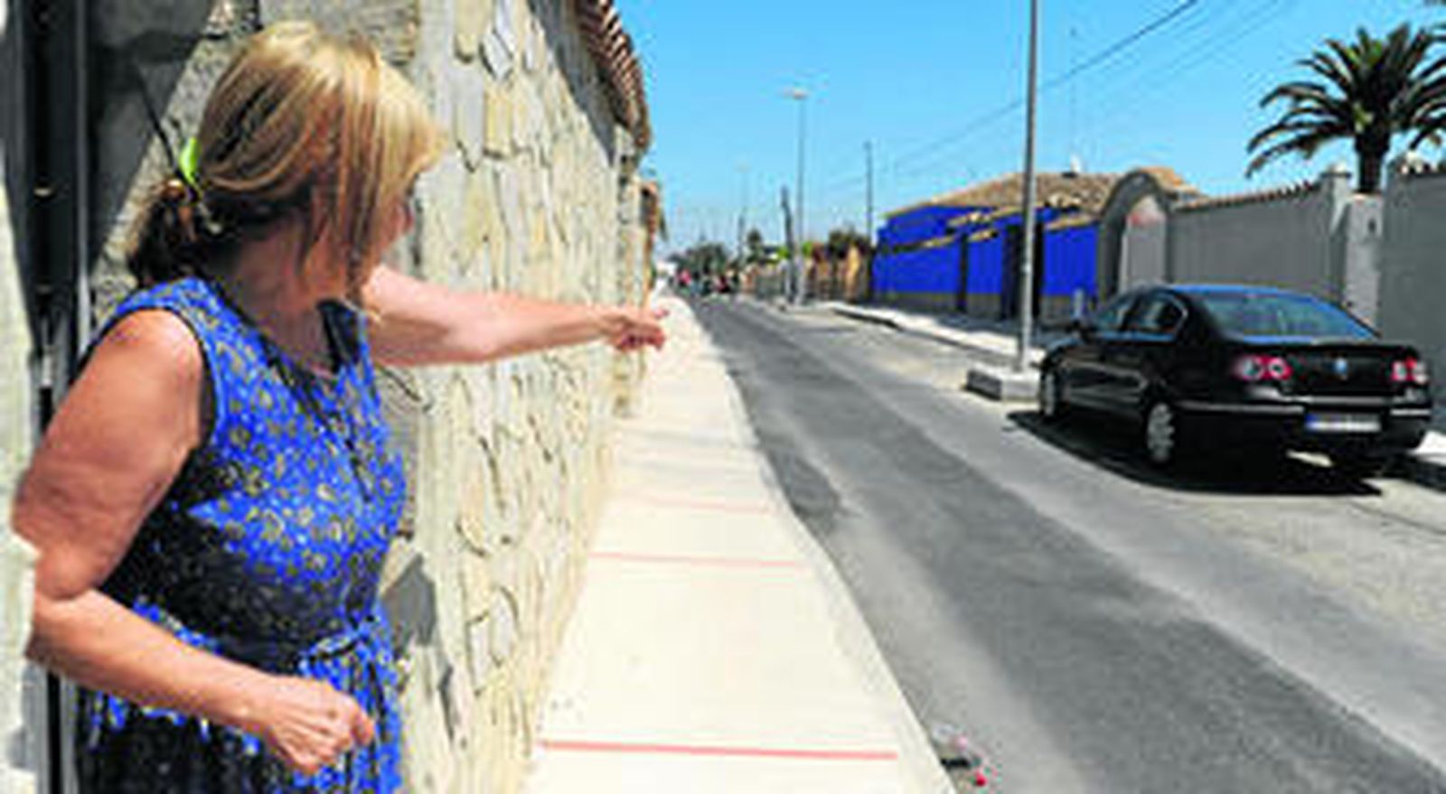 Una vecina muestra cómo sólo se ha asfaltado la mitad de una de las calles, así como otros defectos aún por resolver.