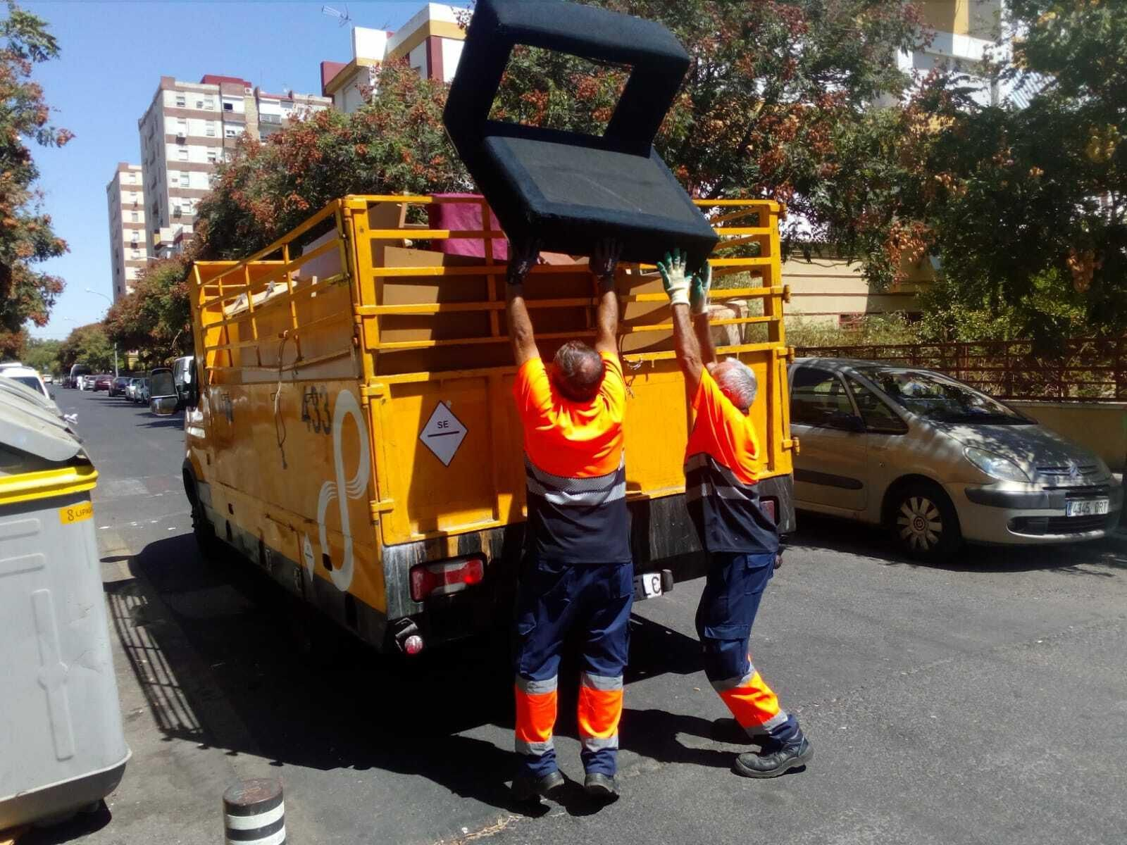 Dos operarios de Lipasam introducen un sofá en un camión de recogida de enseres.