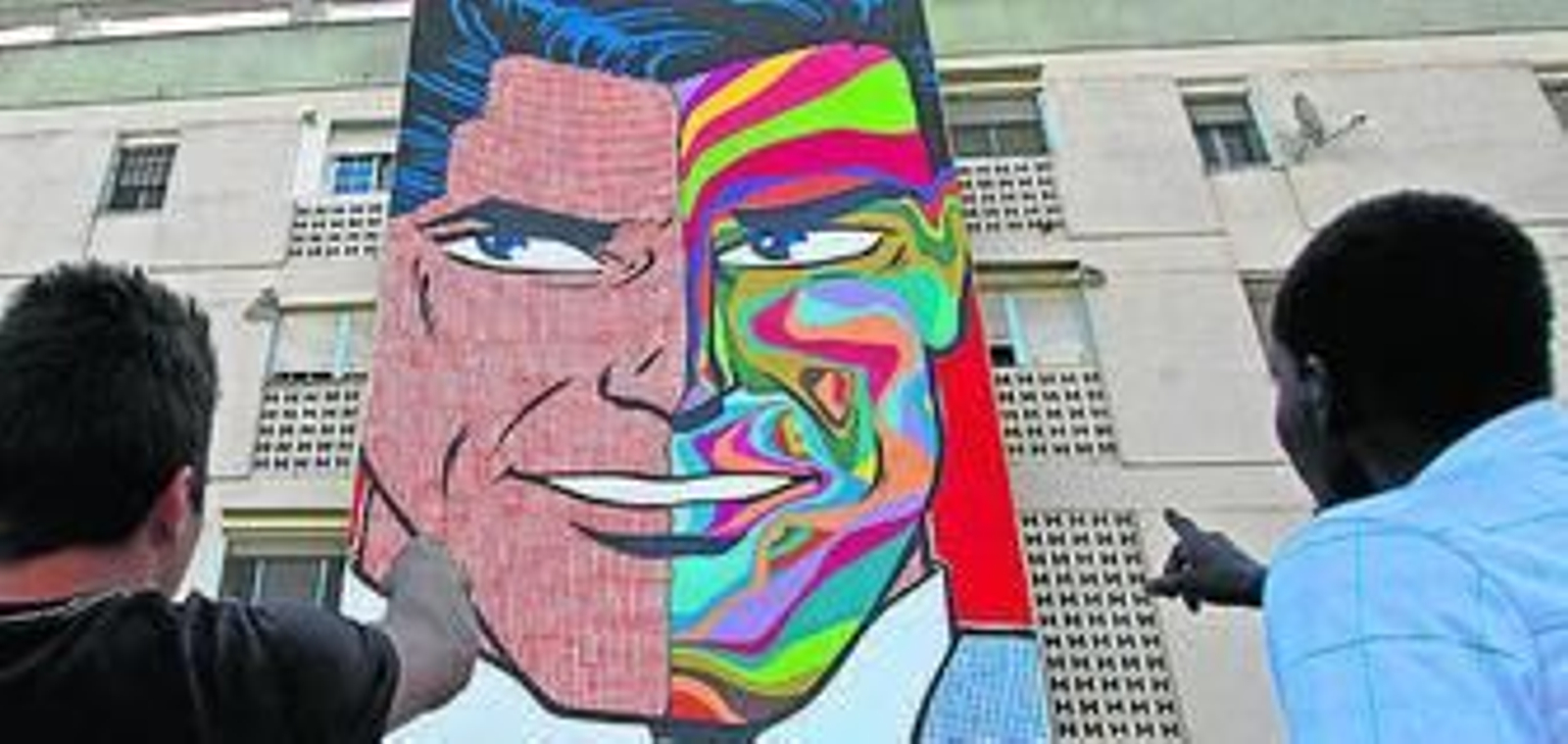 Un bebé en brazos de su madre pintado sobre un bloque de pisos.