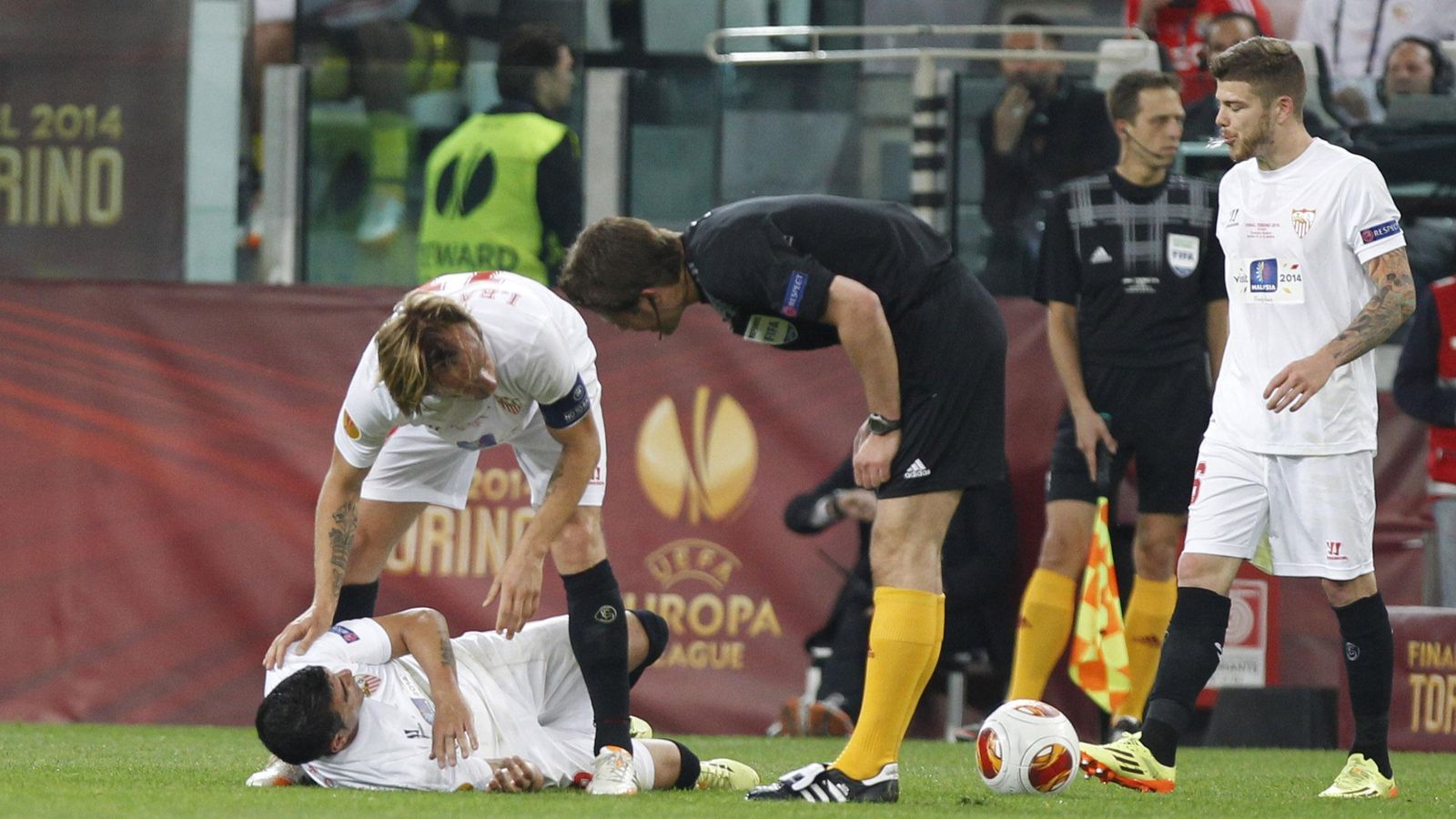 Reyes es atendido por Rakitic durante el partido, junto al árbitro y Alberto Moreno.