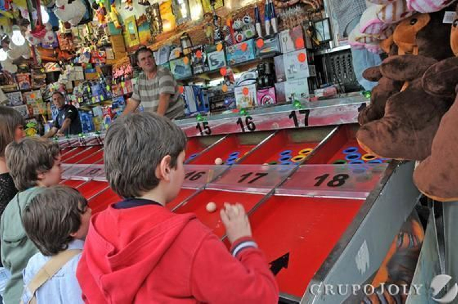 Un grupo de niños prueba suerte y puntería en una tómbola situada a los lados de los cacharritos.

Foto: Manuel Aranda