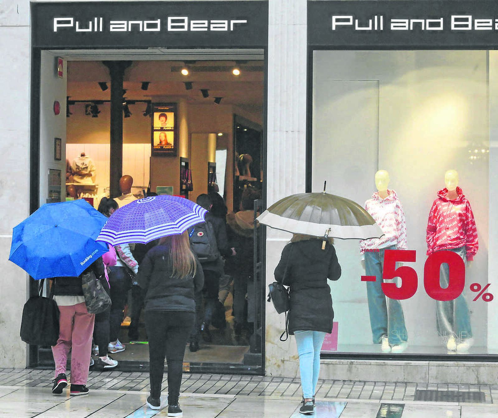 Un grupo de personas se detiene junto a una tienda con descuentos