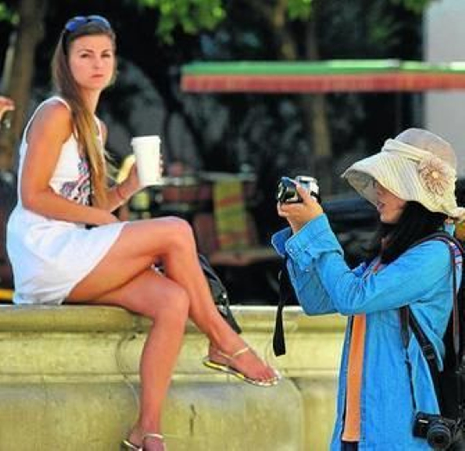 Una turista hace una foto mientras otra bebe un refresco.