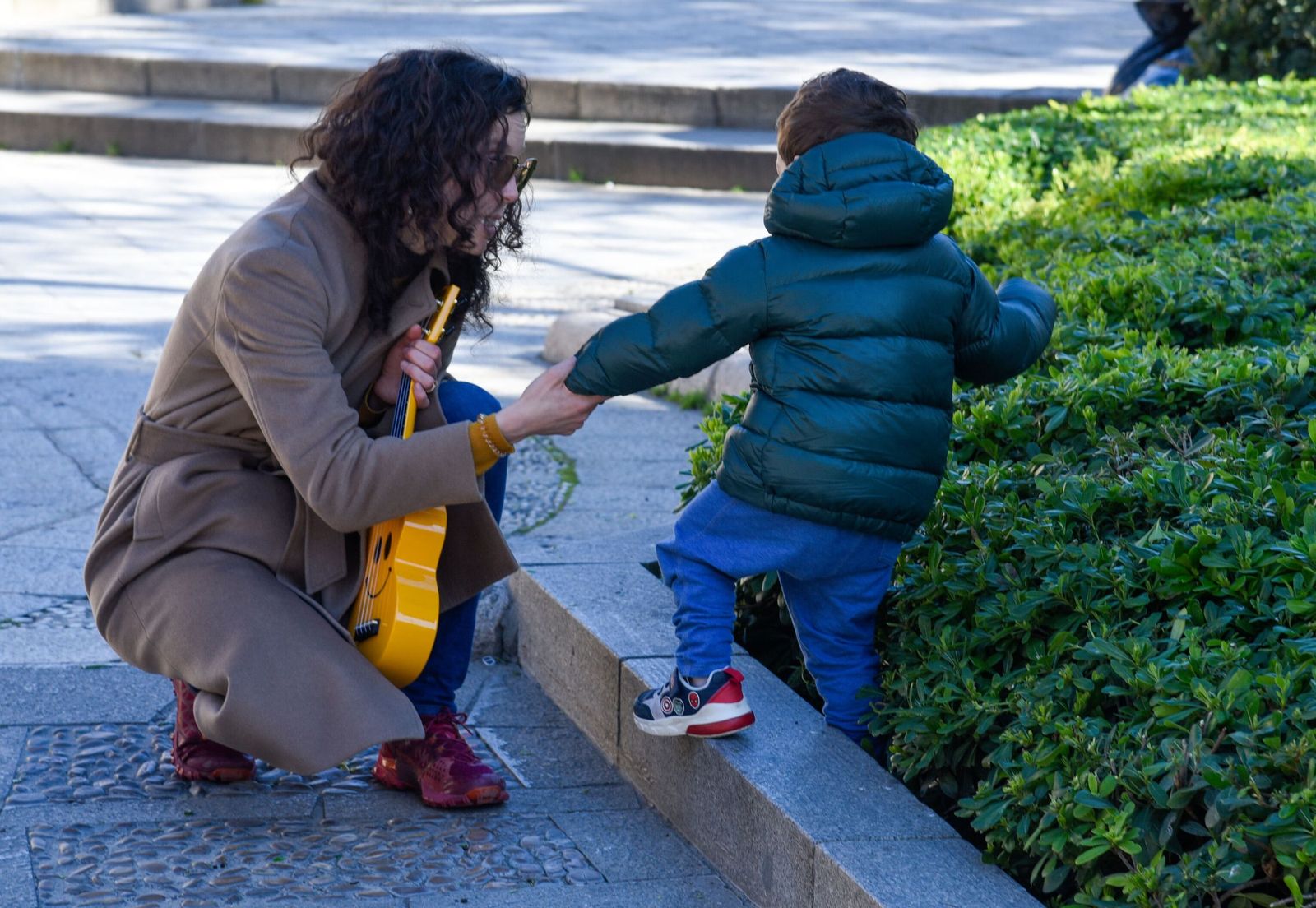 Una madre da la mano a un niño mientras sujeta sus juguetes.