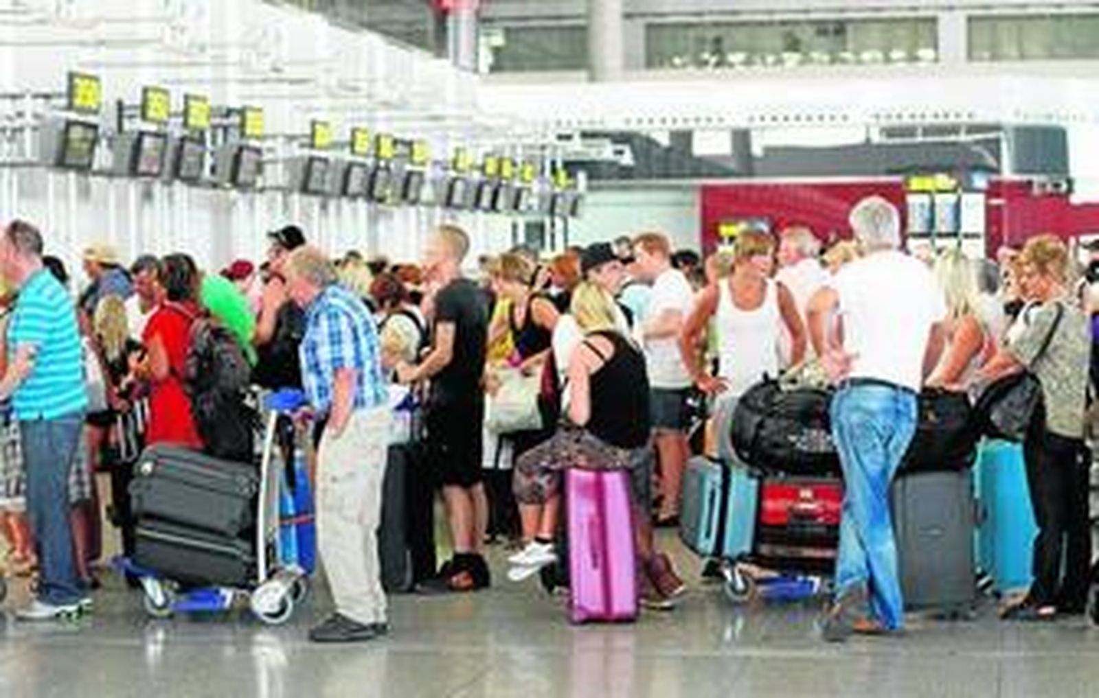Varios turistas hacen cola en el aeropuerto de Málaga para facturar sus maletas.