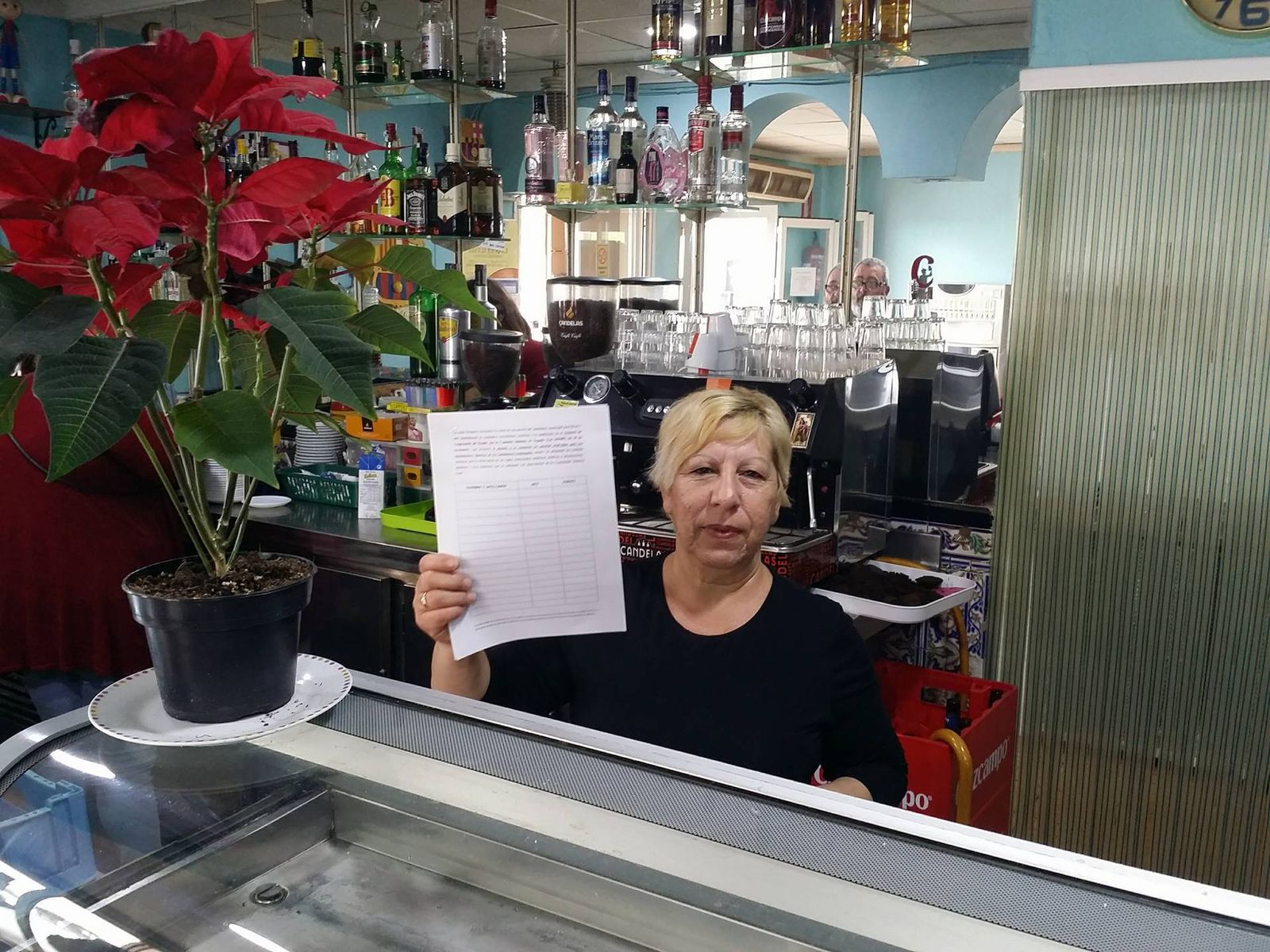 En el Bar Romino de El Saladillo, la trabajadora muestra la hoja para recoger firmas de los ciudadanos.