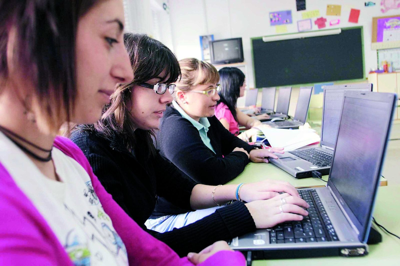 Alumnos con ordenadores en su colegio.
