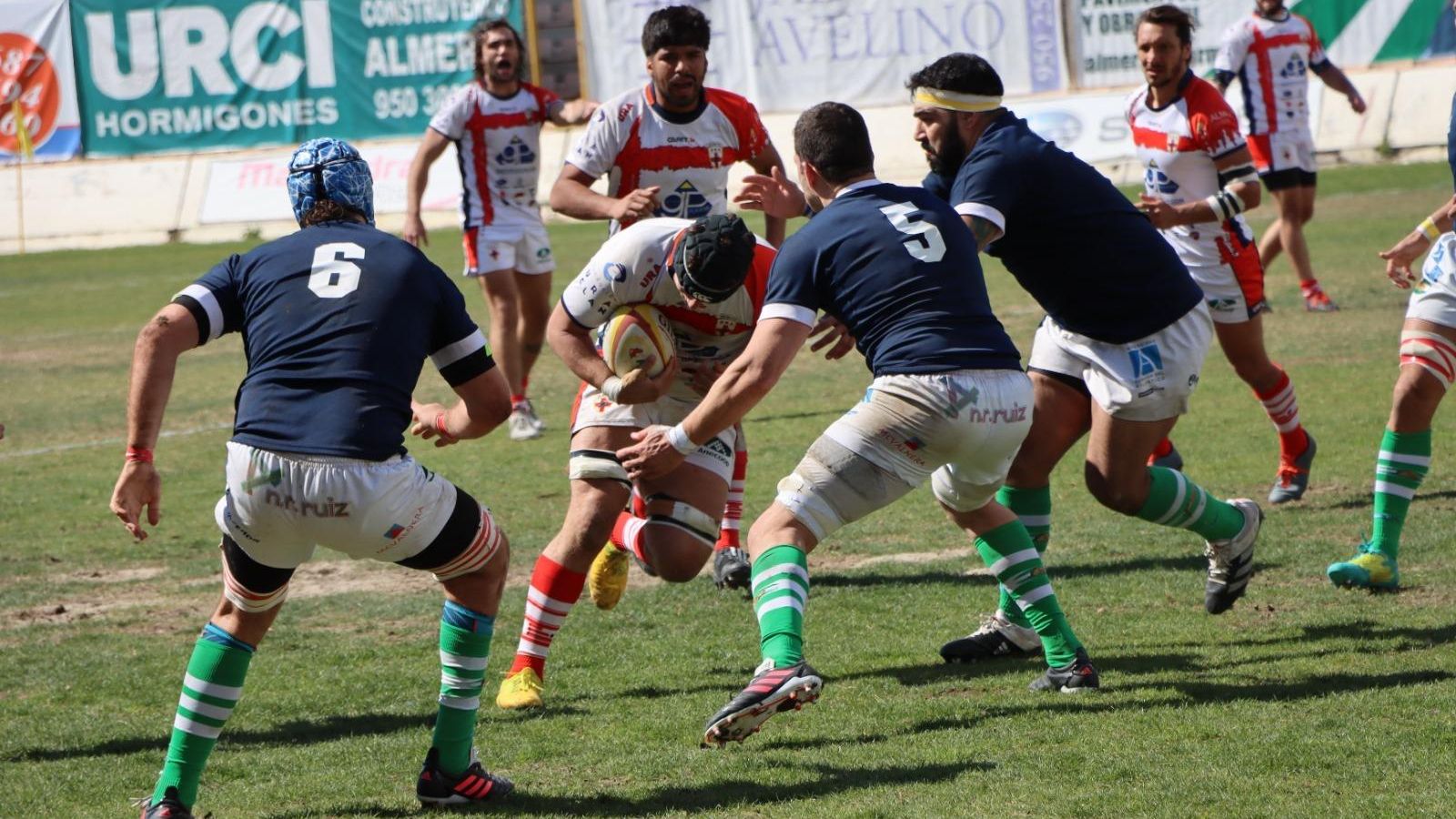 Un jugador local intenta atravesar la línea defensiva visitante