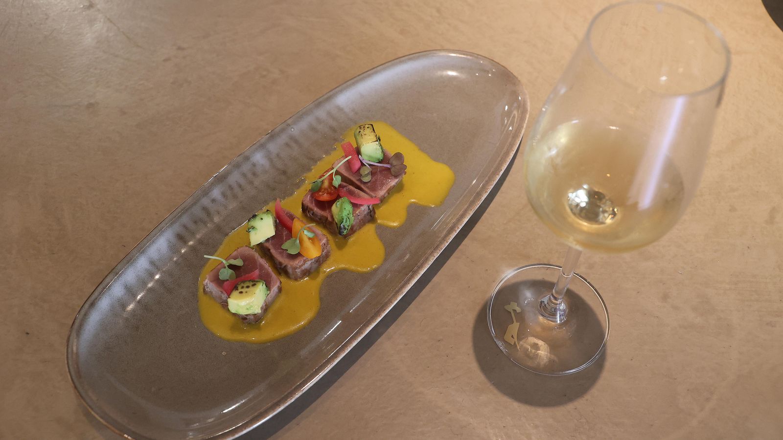 Lomo de atún marinado en ají amarillo y aguacate asado.