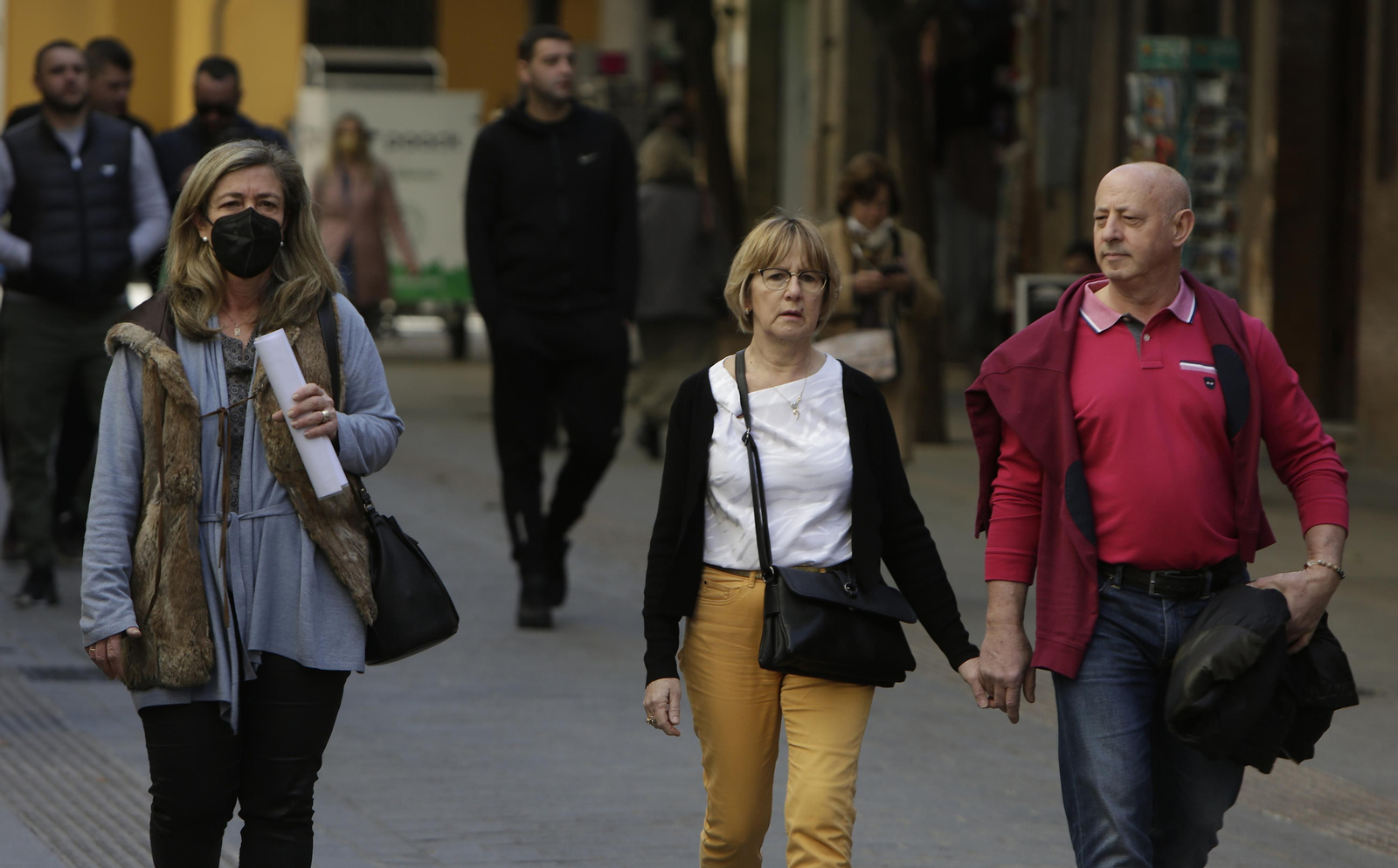 Una mujer con mascarilla entre varias personas sin ella.