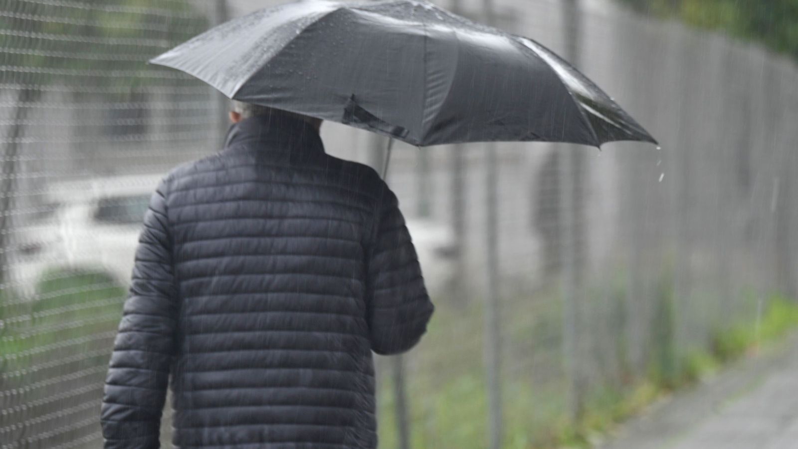Un hombre se protege con un paraguas de un aguacero en la capital.