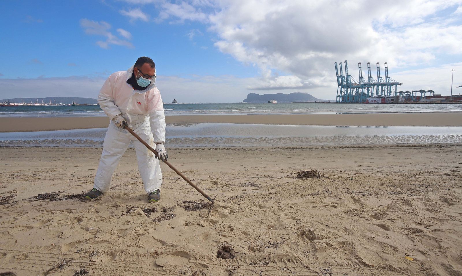 Un operario recoge restos de fuel en la playa del Rinconcillo.