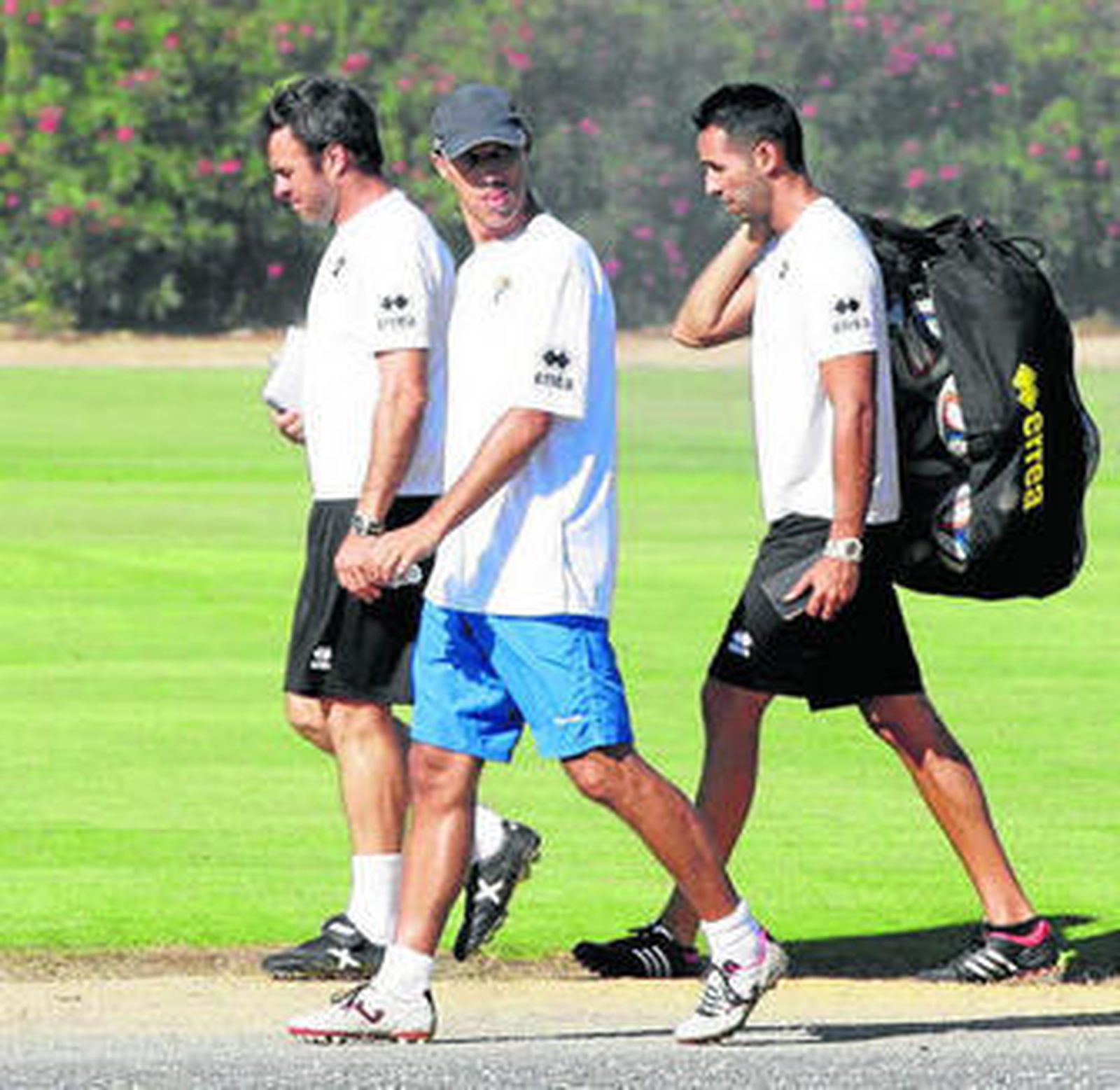 El entrenador camina (c) junto a integrantes de su cuerpo técnico.