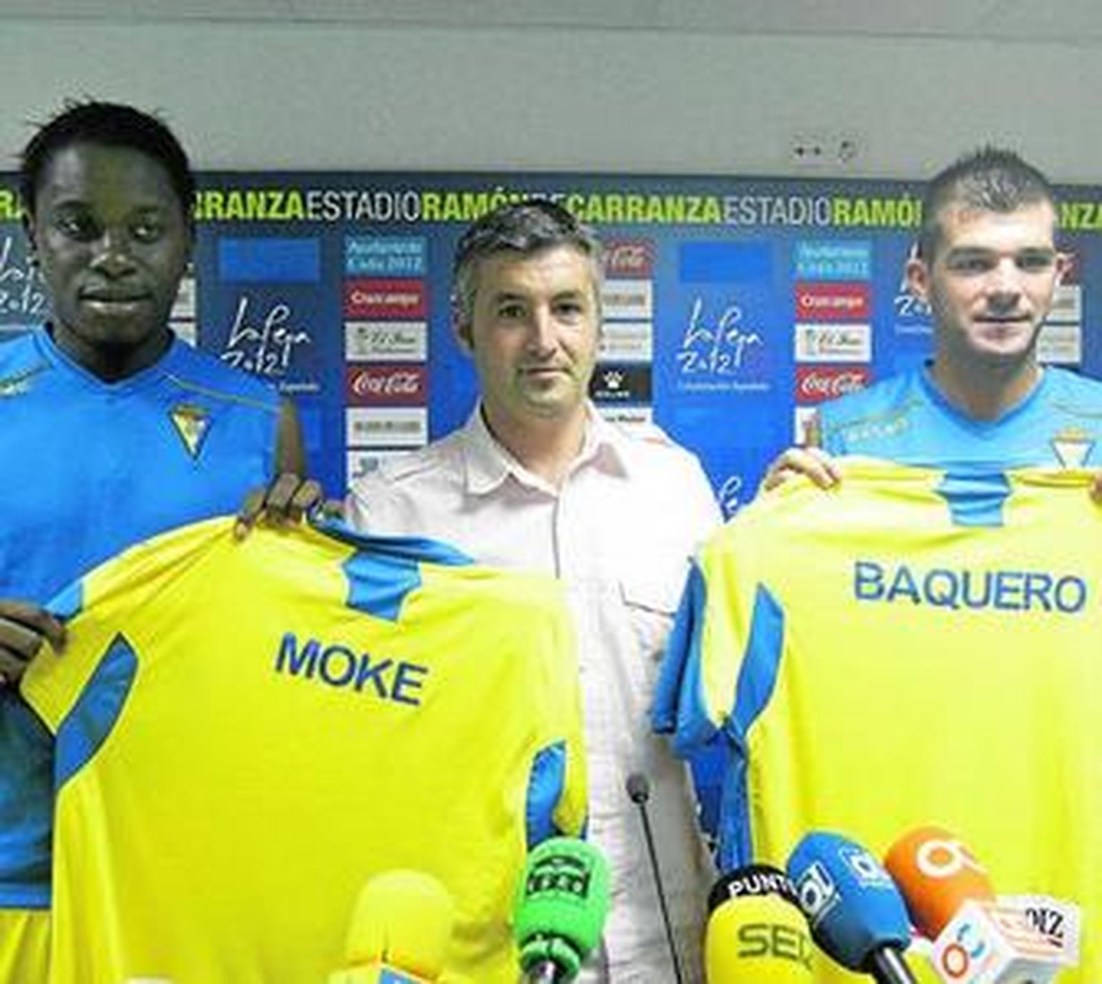 Moke (i) y Baquero sujetan sus nuevas camisetas en presencia de Roberto Suárez.