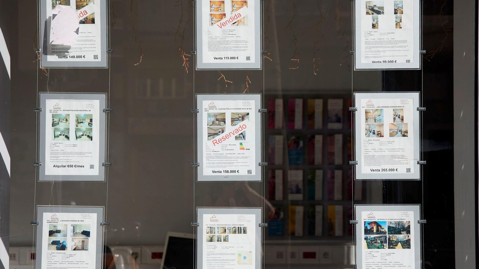 Carteles de vivienda en alquiler y venta en el escaparate de una inmobiliaria.