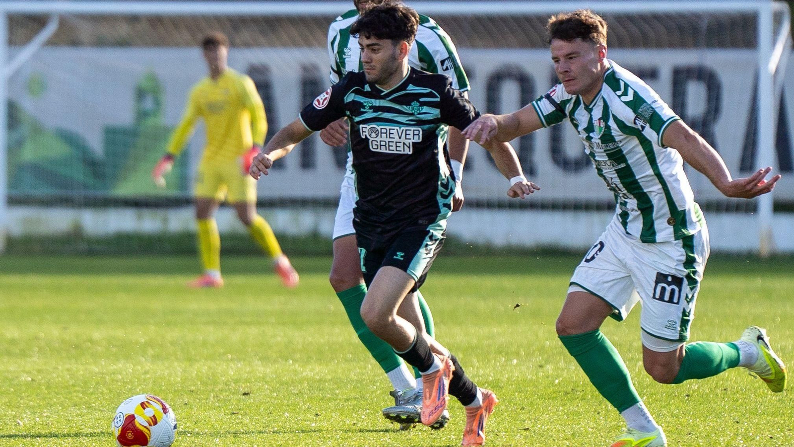 Un jugador del Betis Deportivo trata de marcharse de la presión de un rival.