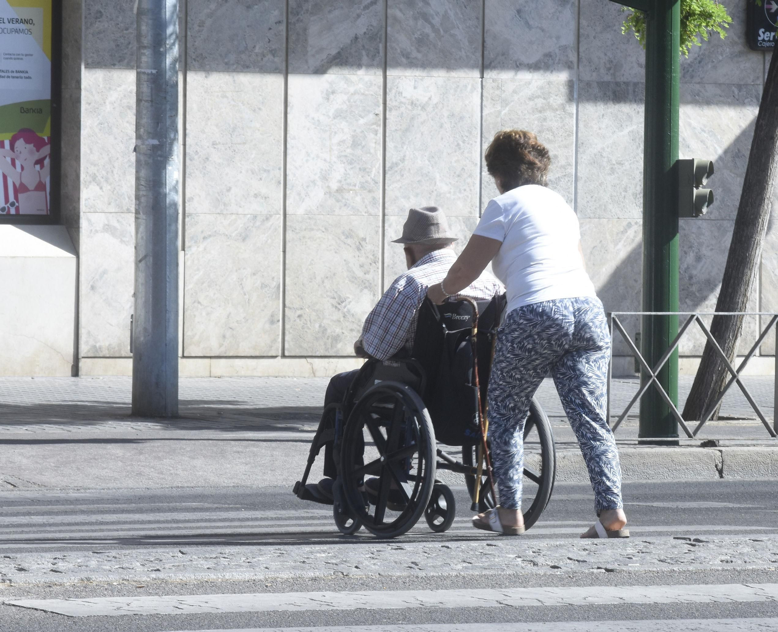 Una mujer conduce a una persona en silla de ruedas en Córdoba.