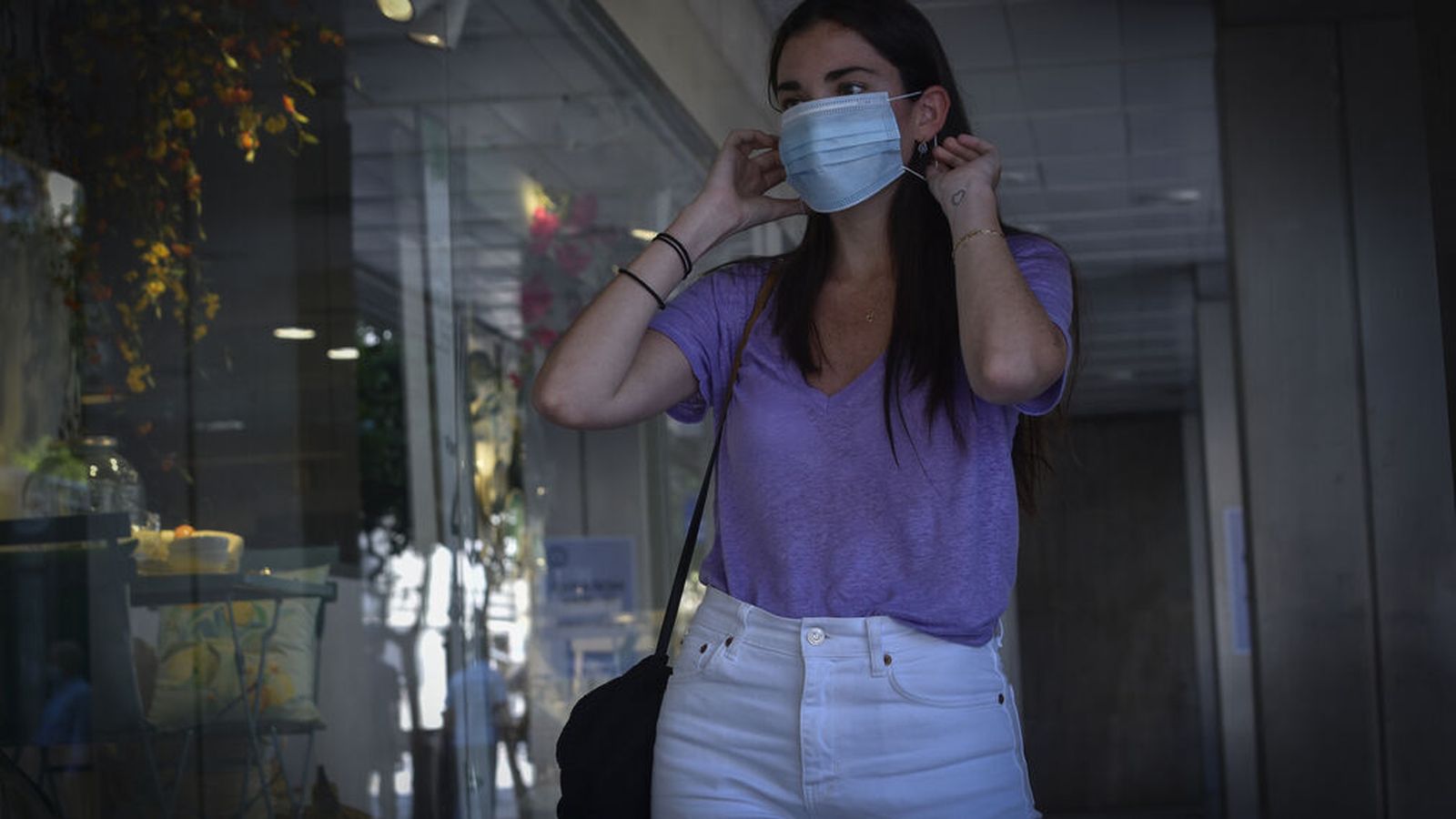 Una joven se pone una mascarilla.