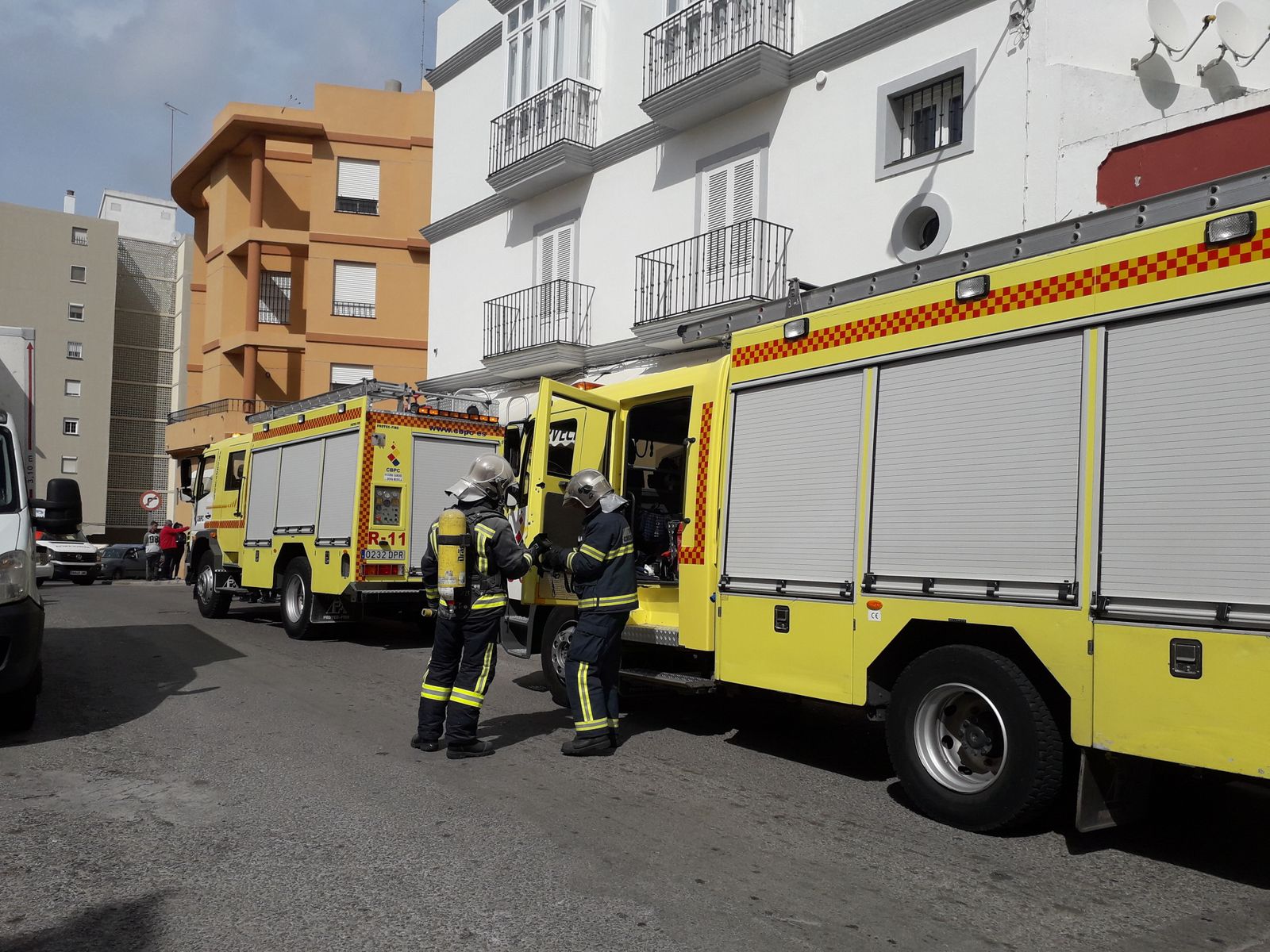 Dos bomberos se preparan para adentrarse en la cocina del local.