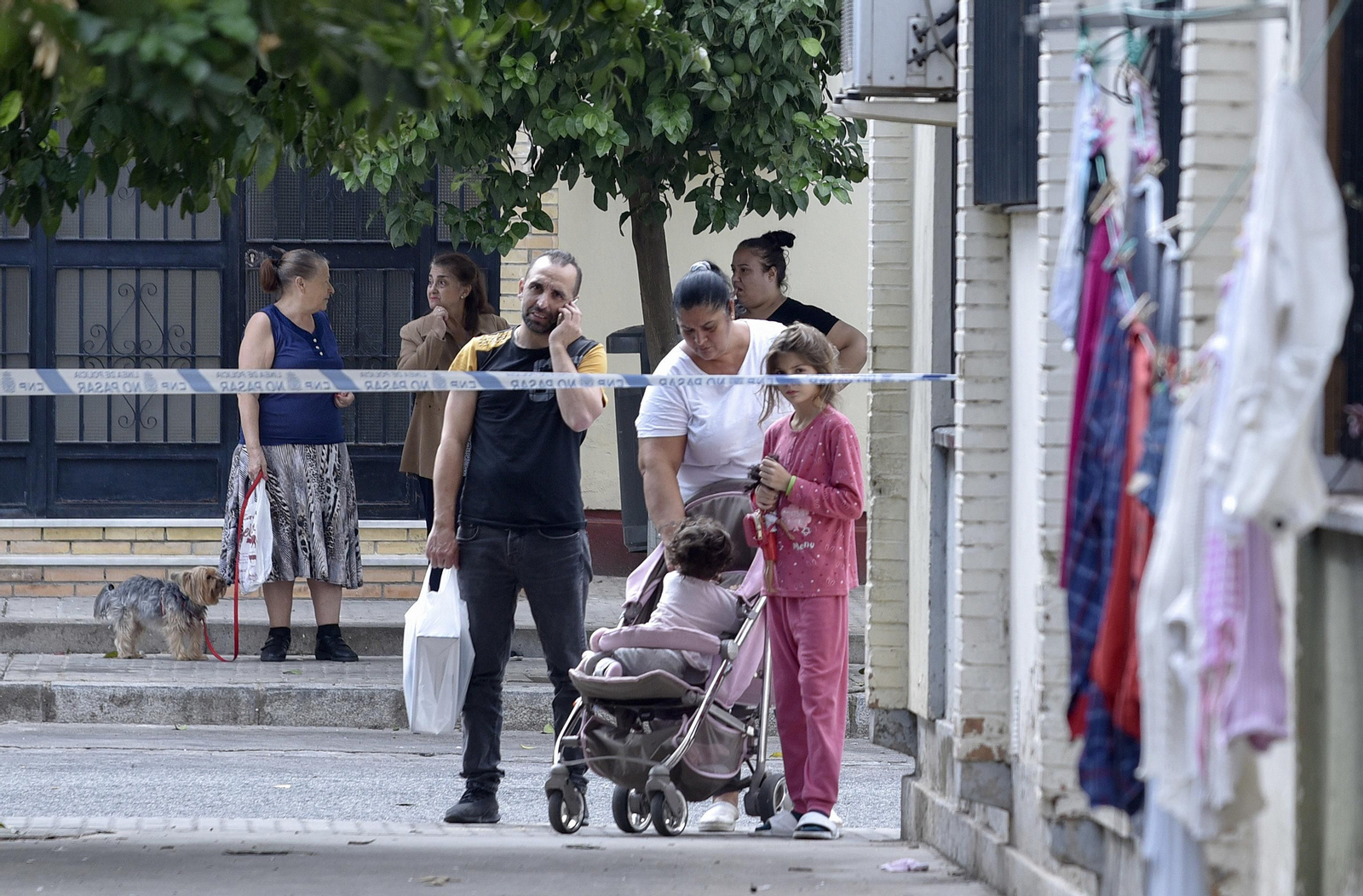 Varios vecinos observan tras el cordón policial.