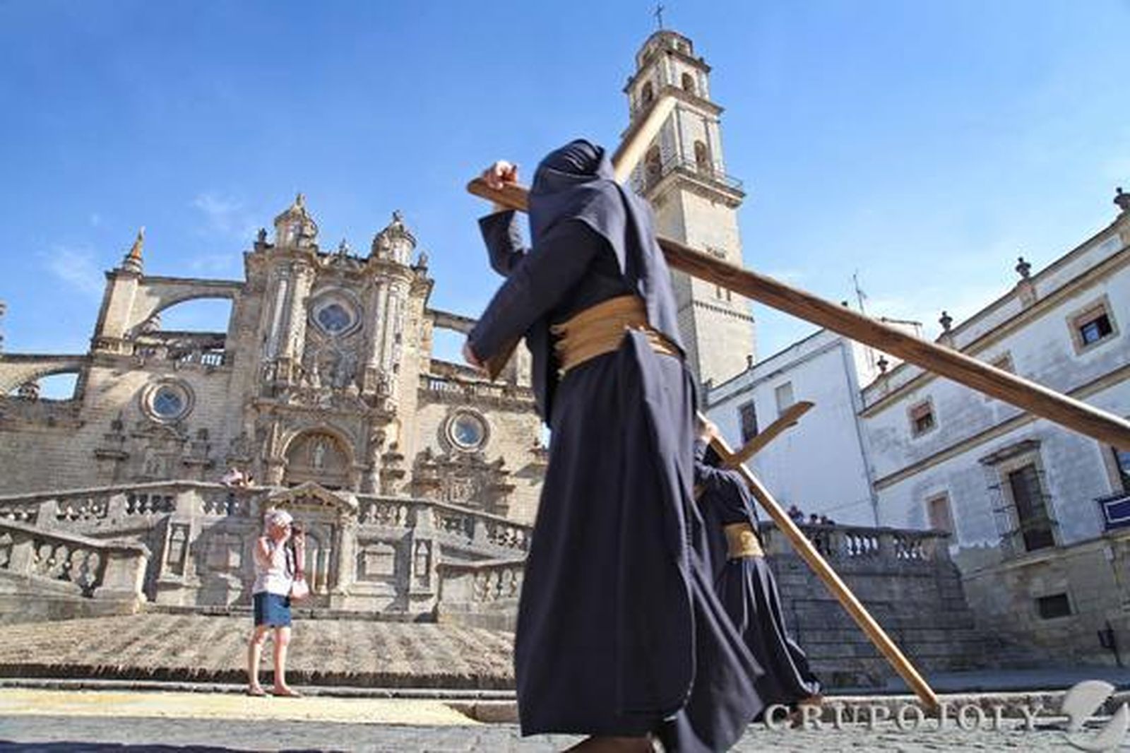La fila de penitentes con cruces de la hermandad del Perdón, a la altura de la Santa Iglesia Catedral en su búsqueda de la Carrera Oficial.

Foto: Vanesa Lobo