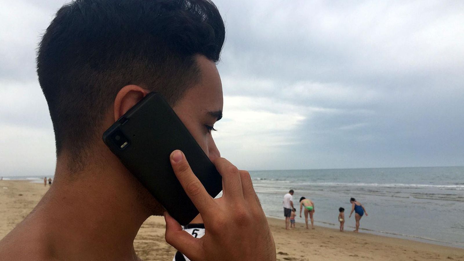 Joven hablando por su teléfono móvil en la playa. Archivo