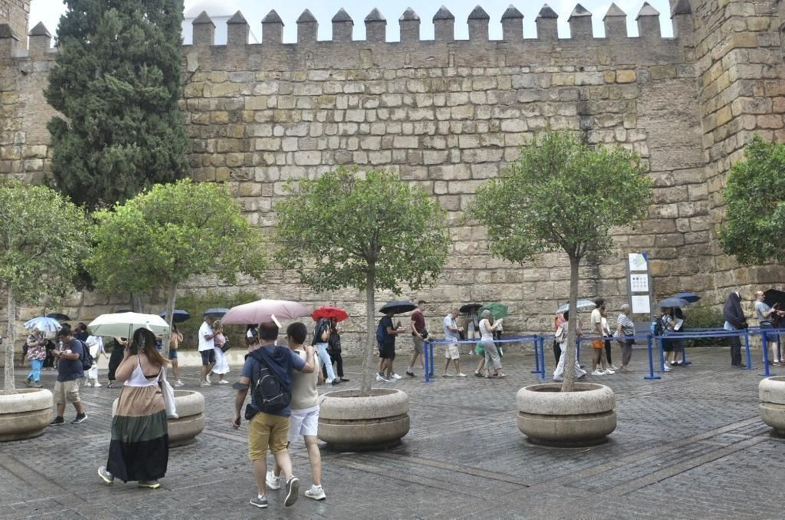 Turistas con paraguas, este martes, junto a la muralla del Alcázar.