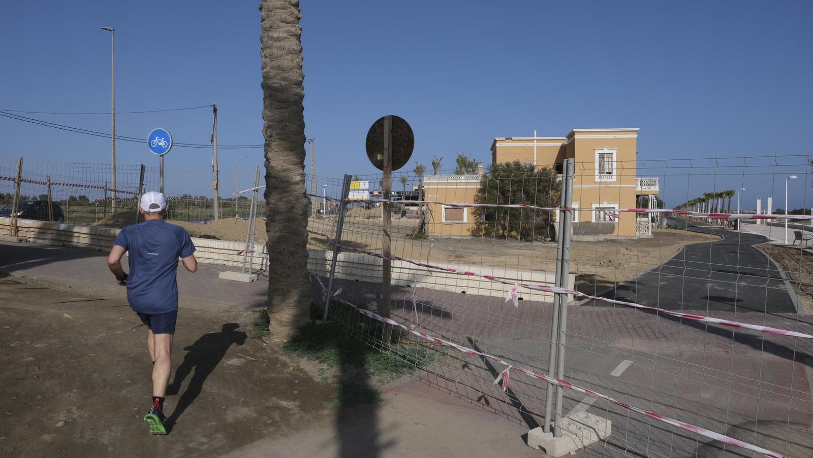 Un hombre corre junto a la valla protectora de las obras