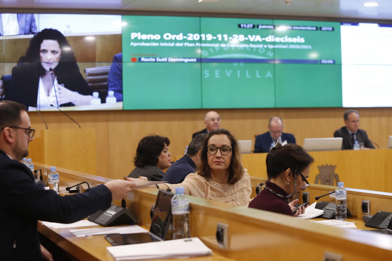 La portavoz de Adelante, María Izquierdo, entrega documentación a uno de sus compañeros durante un Pleno.