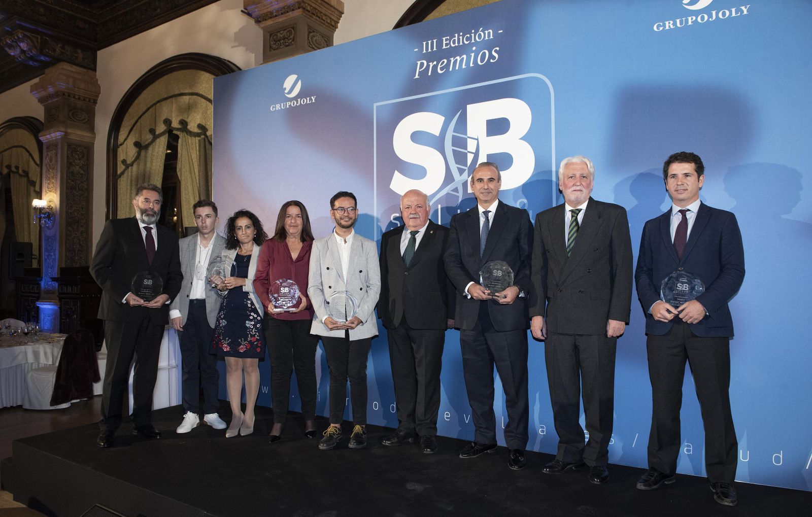 Foto de familia de todos los premiados, tanto en la segunda como en la tercera edición, con el consejero de Salud, Jesús Aguirre, y el presidente del jurado, el doctor Jesús Castiñeiras.