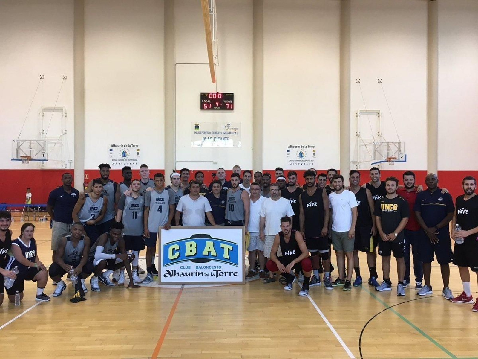 Fotografía de familia de los dos equipos al terminar el amistoso sobre el parqué del pabellón de Alhaurín de la Torre.