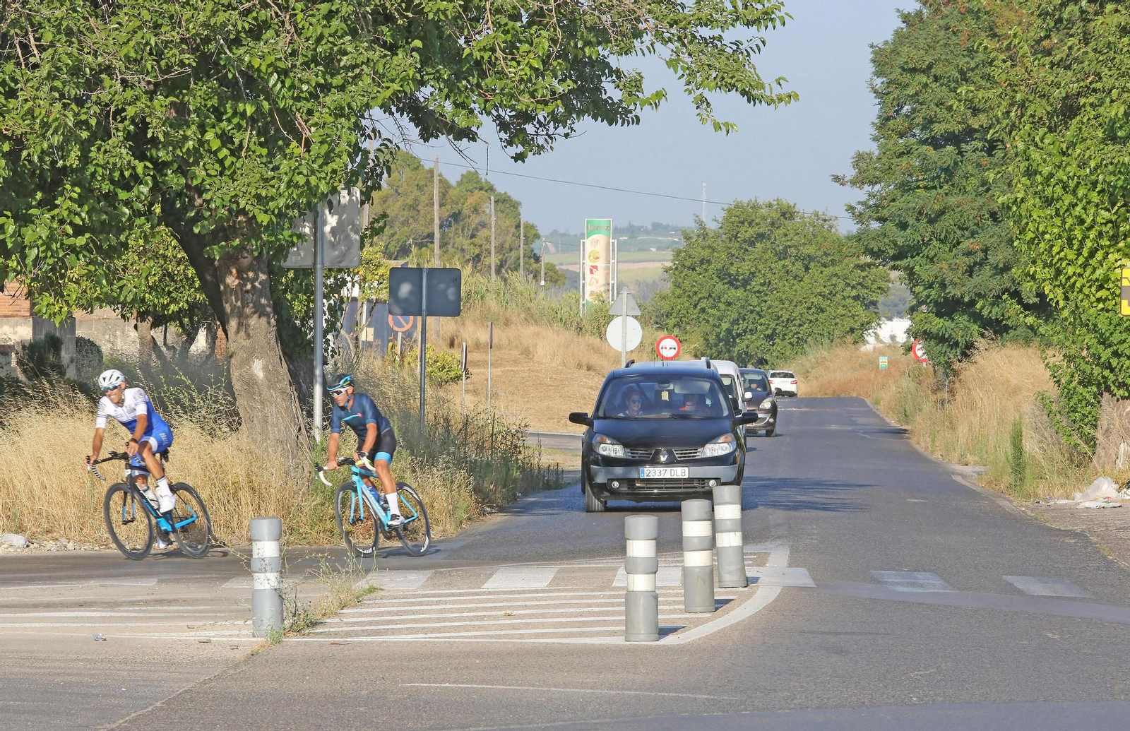 Varios vehículos circulan por la carretera A-2003, a la altura del cementerio.