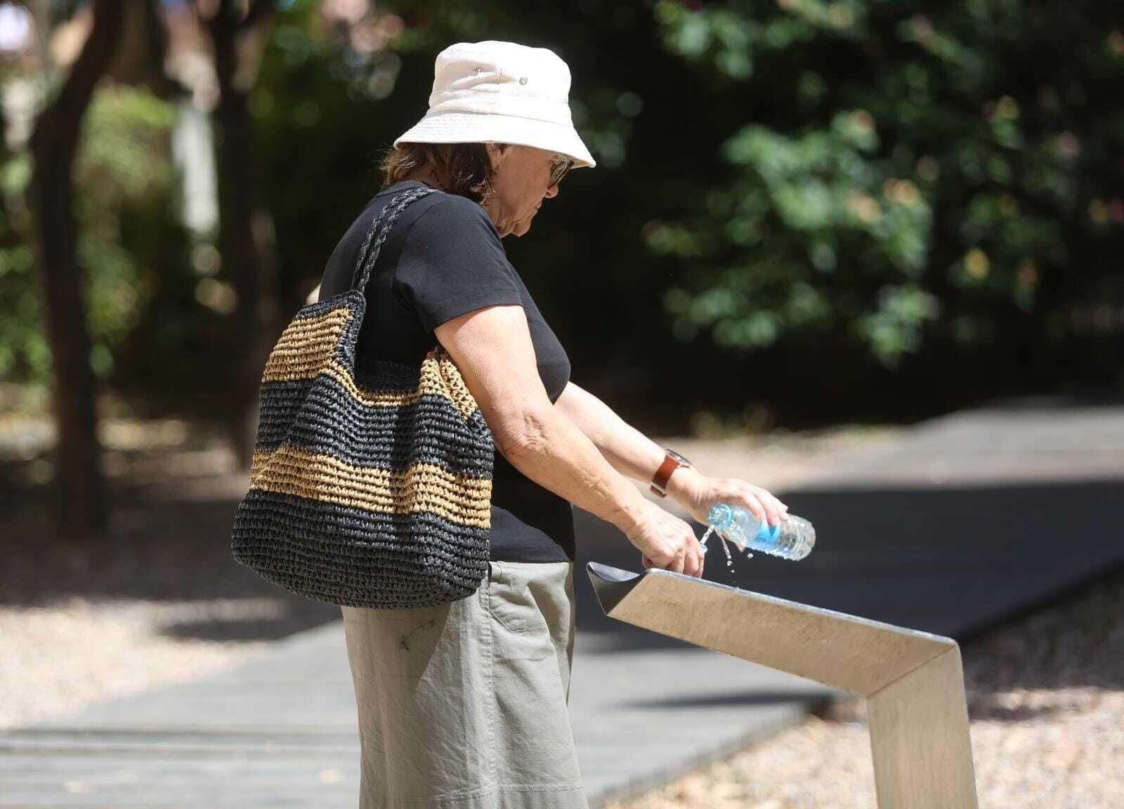 Una mujer rellena su botella de agua en una fuente de Málaga.